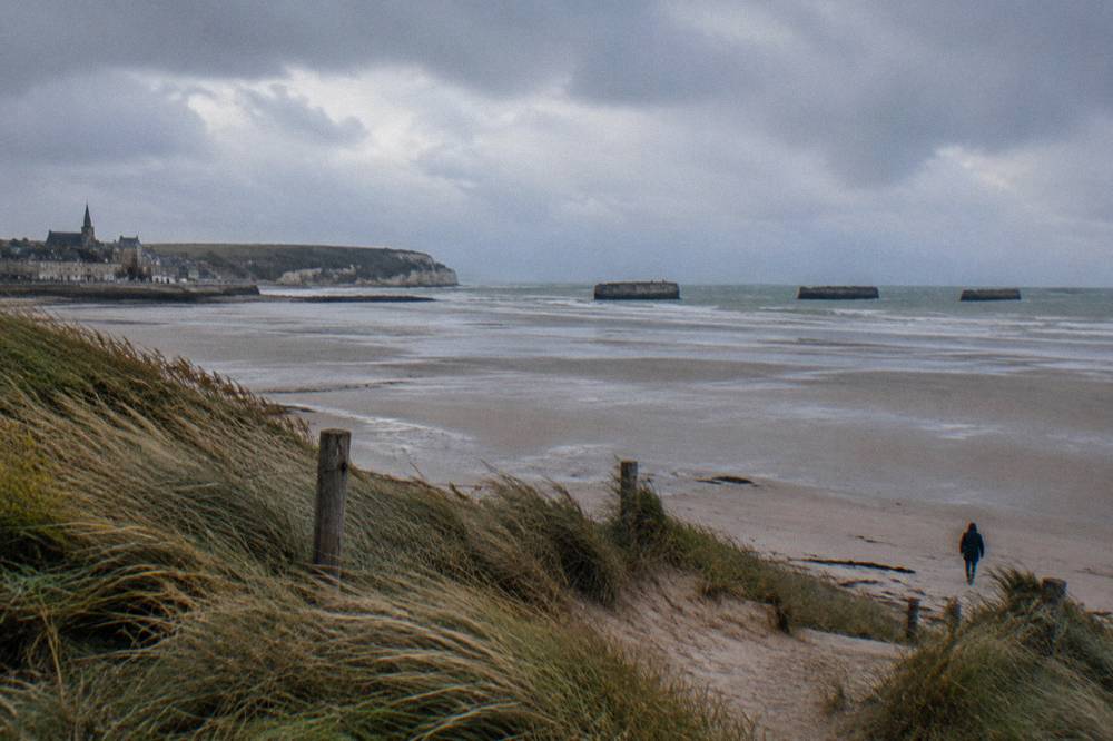 Dark Mulberry harbour caissons at Arromanches seen across the empty beach