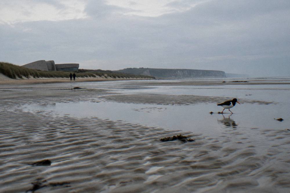 Wide rippled sandflat at Utah Beach at low tide under pale grey light