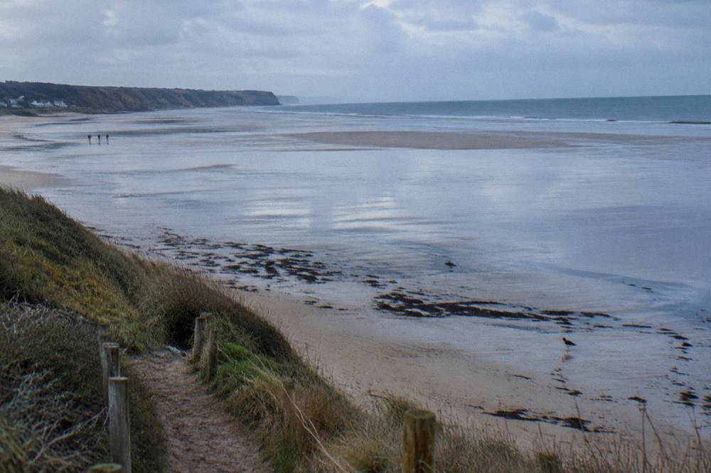 Wide flat Omaha Beach at low tide seen from the dune path